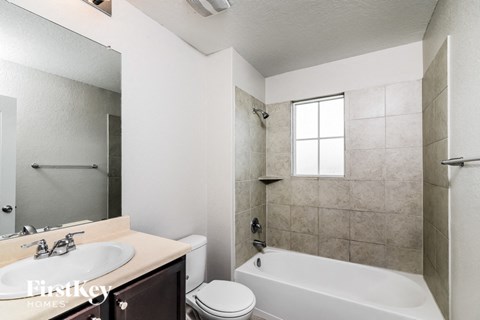 A bathroom with a white tub, sink, and toilet.