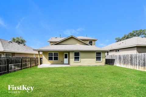 A house with a fence and a green lawn in front of it.