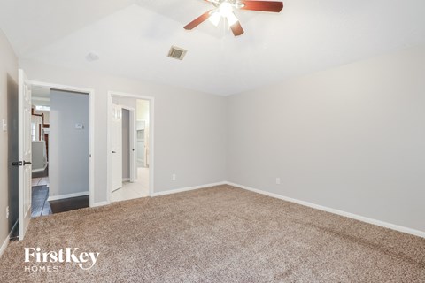 a spacious living room with carpet and a ceiling fan