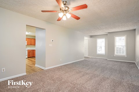 A spacious room with a ceiling fan and carpeted floor.