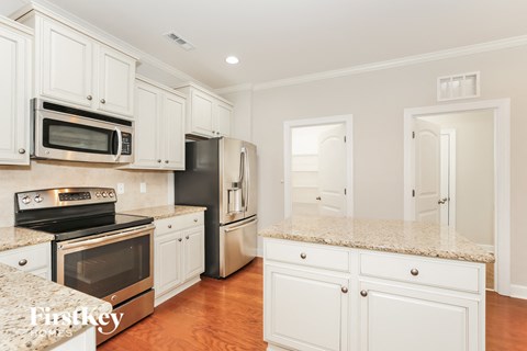 A kitchen with white cabinets and granite countertops.