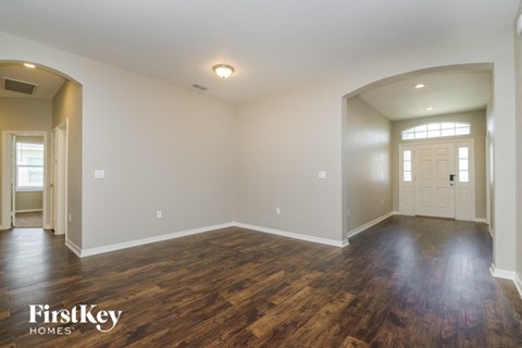 A spacious room with wooden floors and white walls, branded with "FirstKey Homes".