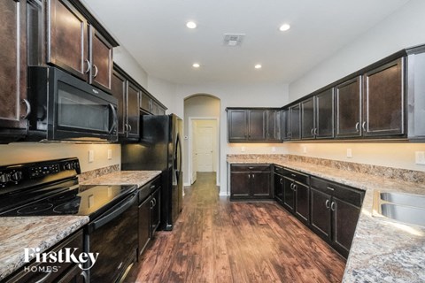 A kitchen with black appliances and wooden floors.