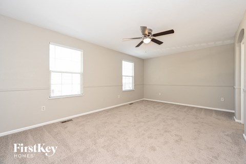 a spacious living room with carpet and a ceiling fan