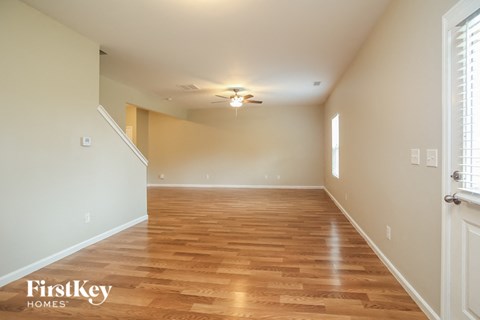 a empty living room with a wood floor and a ceiling fan