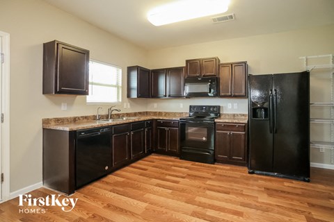 an empty kitchen with black appliances and wood flooring