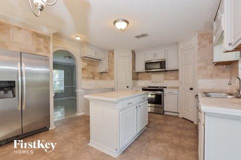 A kitchen with a refrigerator, sink, and microwave.