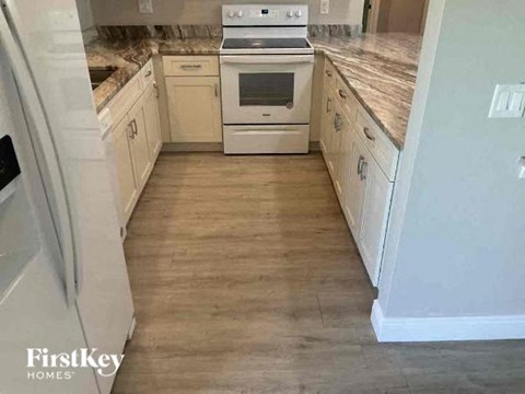 A kitchen with white appliances and wooden floors.