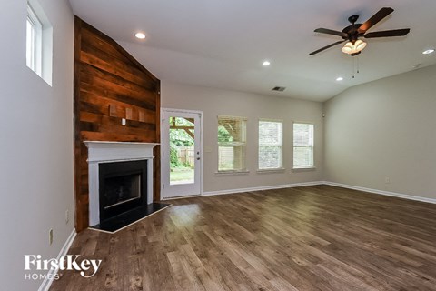 A spacious room with a fireplace and a ceiling fan.