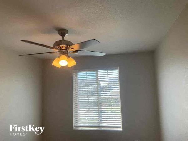 a ceiling fan with a light in a room with a window