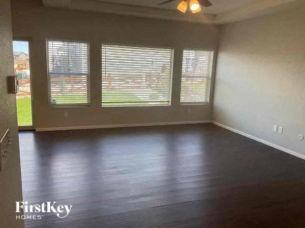 an empty living room with a wood floor and three windows