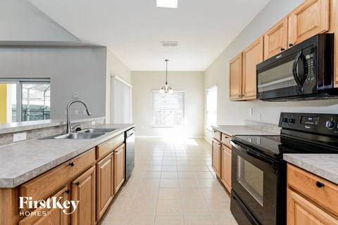 A kitchen with wooden cabinets and a black microwave.