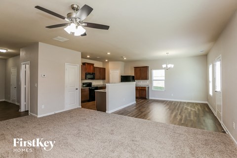 A spacious living room with a ceiling fan and lighting fixtures.
