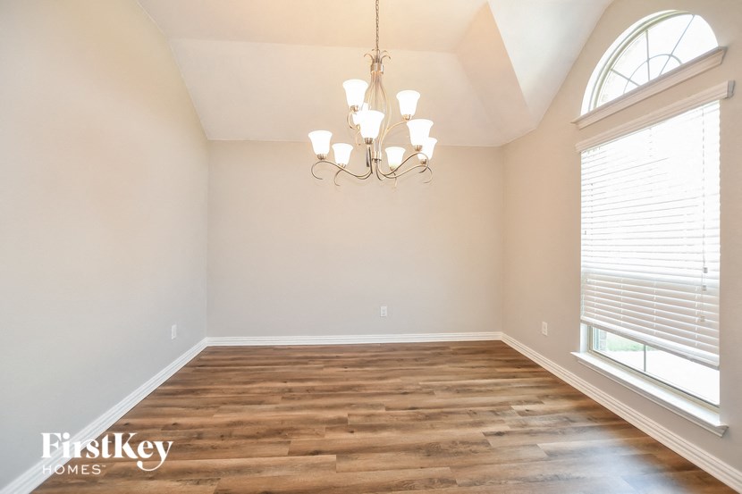 an empty dining room with wood flooring and a chandelier