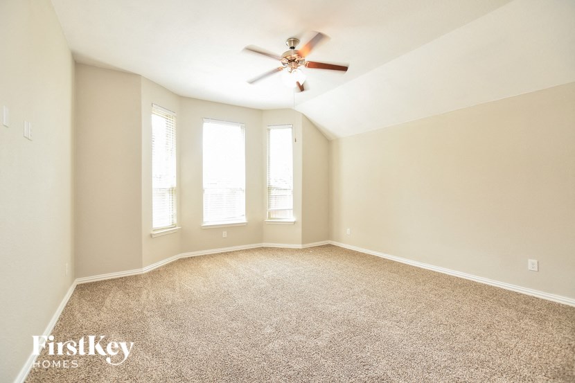 an empty living room with a ceiling fan and three windows