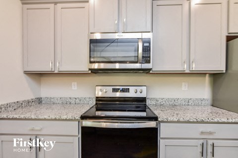 a kitchen with white cabinets and a stove and a microwave