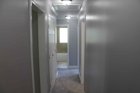 a hallway with a door to a bathroom and a closet with a window