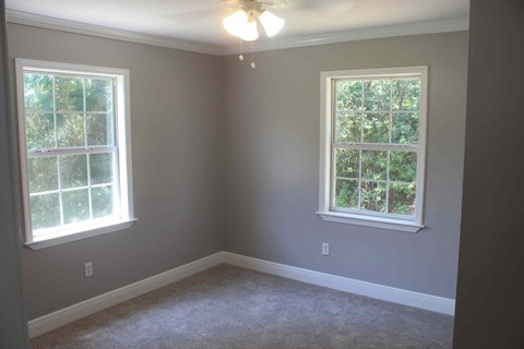 a empty room with two windows and a ceiling fan