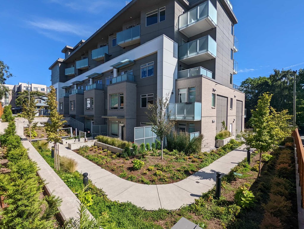 A modern apartment building with a landscaped garden in front.