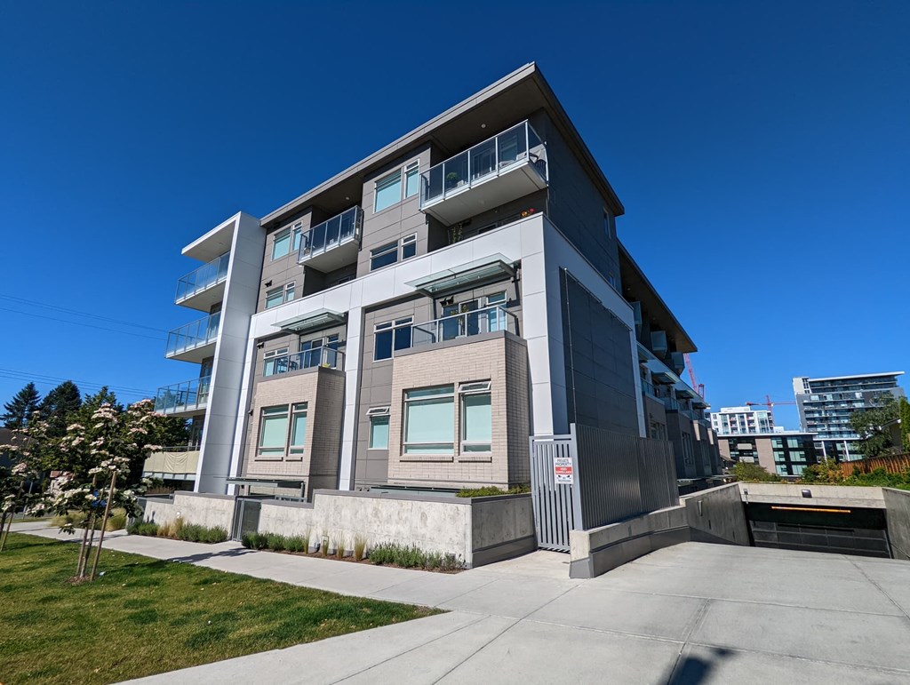 A modern building with a grey and white exterior and a clear blue sky in the background.