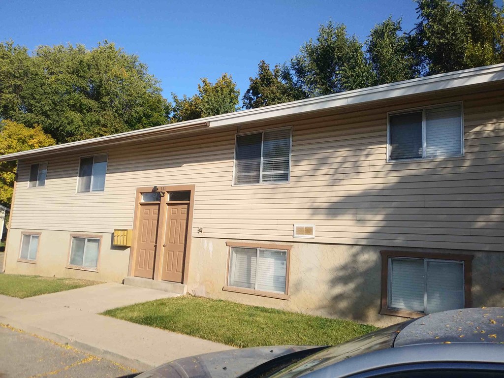 A beige house with a brown door and windows.
