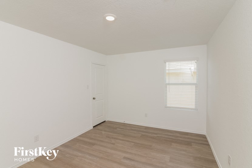 the living room of a home with white walls and wood floors