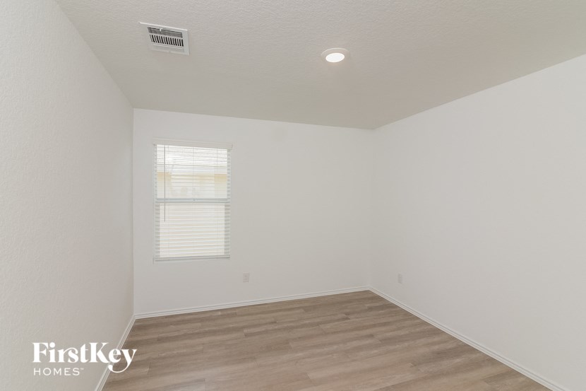 a bedroom with white walls and wood flooring and a window