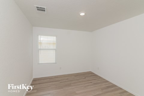 a bedroom with white walls and wood flooring and a window