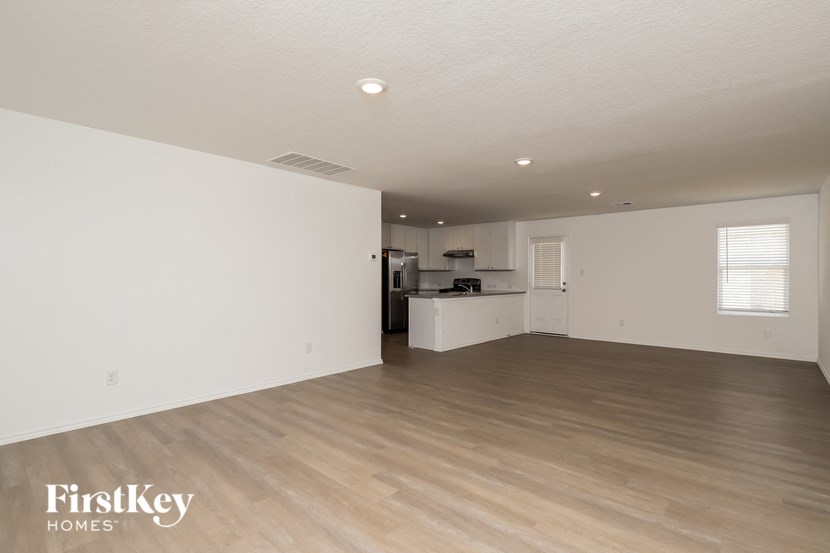 an empty living room and kitchen with wood flooring