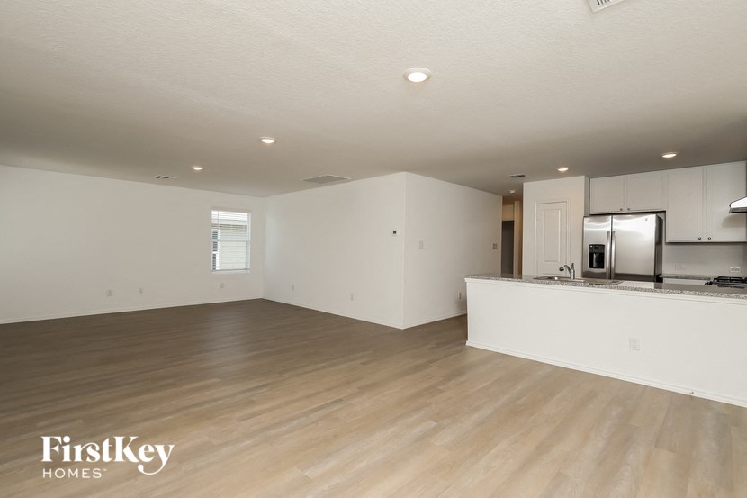 an empty living room and kitchen with a wood floor