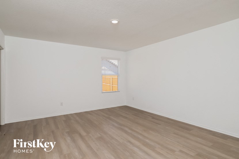 a bedroom with white walls and wood flooring and a window