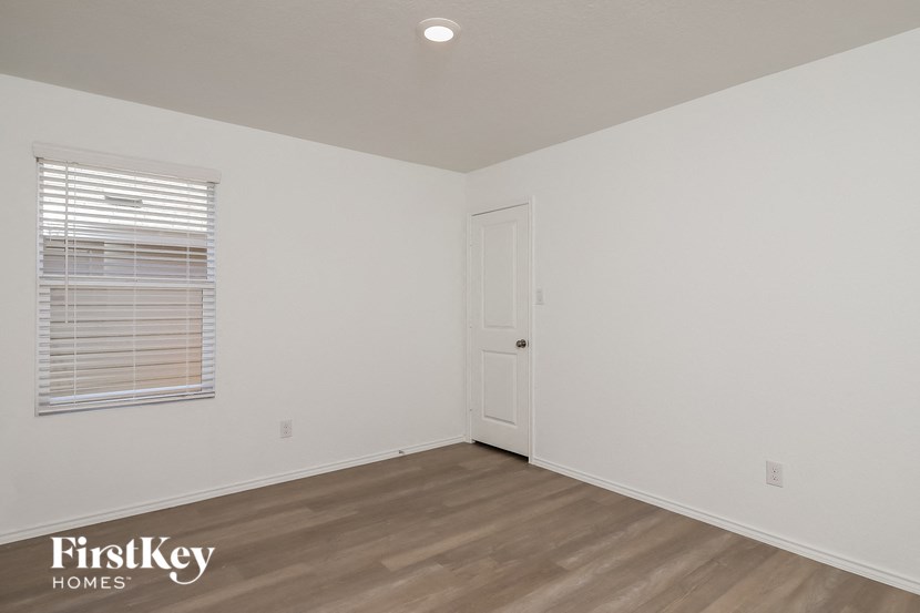 a bedroom with white walls and wood flooring and a window