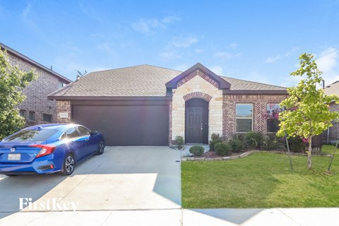A blue car is parked in front of a brick house.