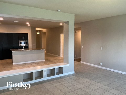 A spacious living room with a kitchen area in the background.