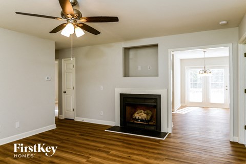 A living room with a fireplace and a ceiling fan.