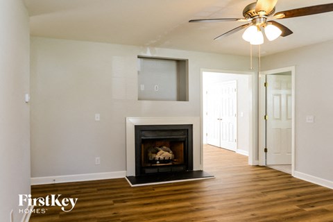 A living room with a fireplace and a ceiling fan.
