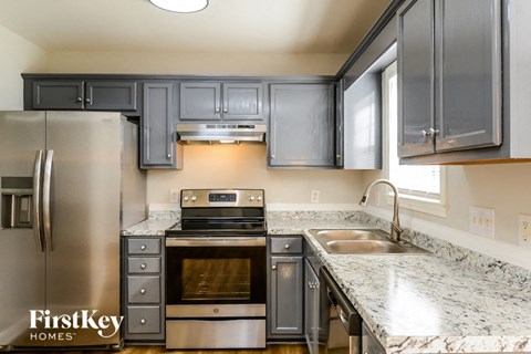 A kitchen with a stainless steel refrigerator and a marble countertop.