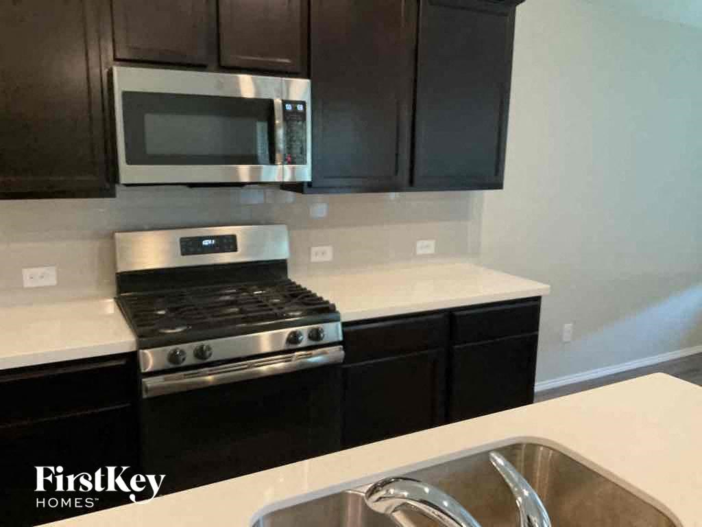 A kitchen with a stove top oven and a microwave above it.