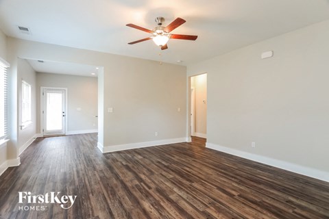 A spacious room with wooden floors and a ceiling fan.