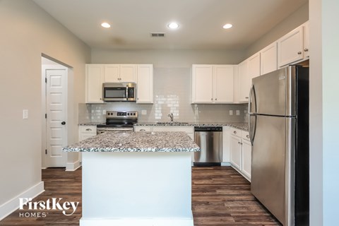 A kitchen with a white island and stainless steel appliances.