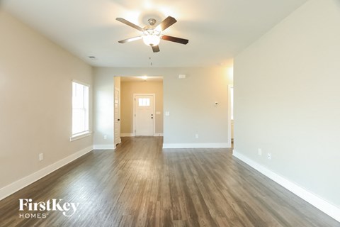 A spacious room with a ceiling fan and wooden flooring.