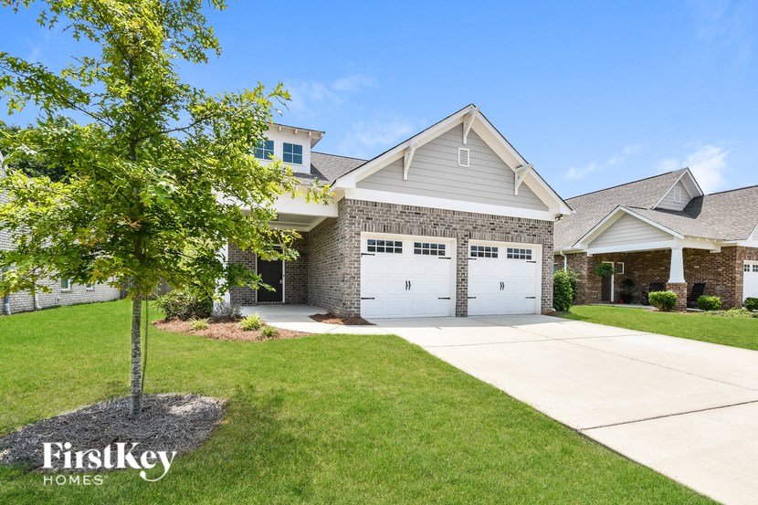 a house with a white garage door and a tree in the yard