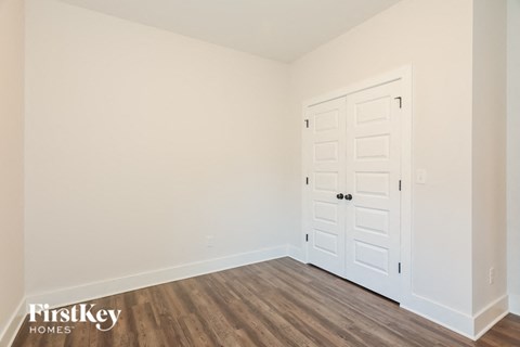 the living room of a home with a white door and wooden floors