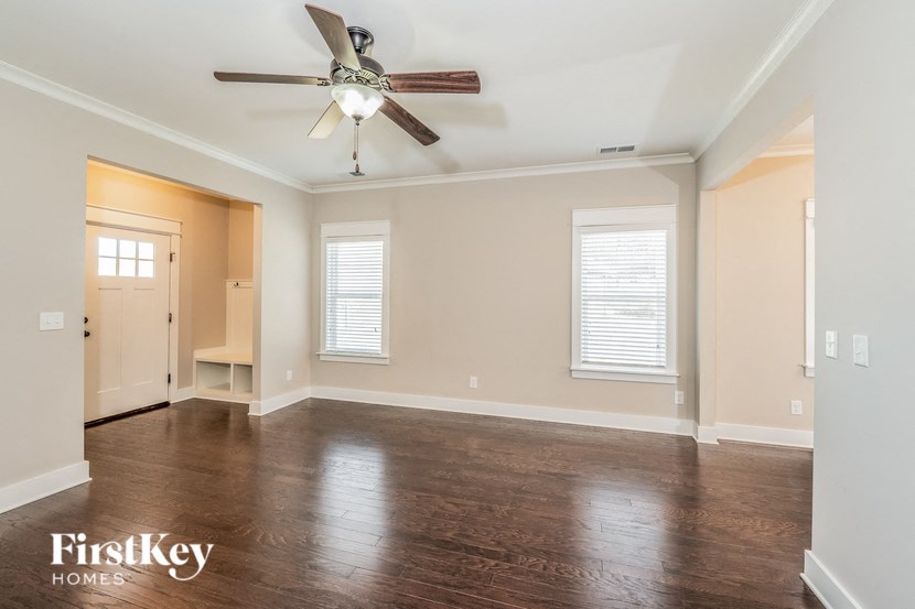 a empty living room with a ceiling fan and wood floors