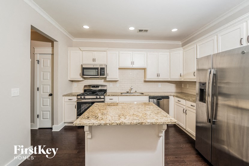 a white kitchen with stainless steel appliances and marble counter tops