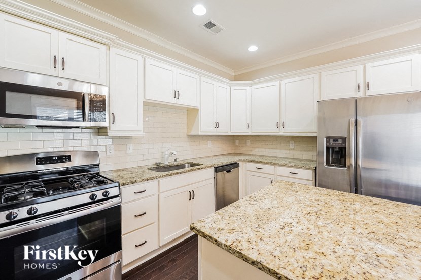 a kitchen with white cabinets and granite counter tops