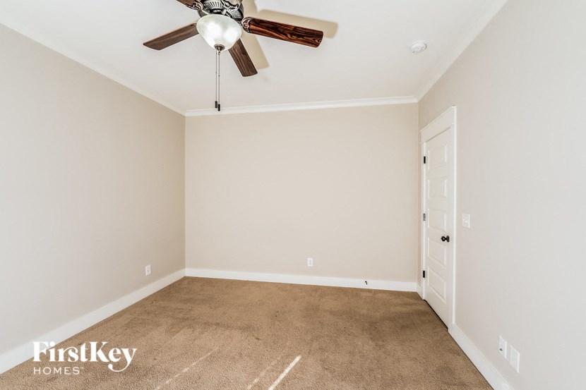 a carpeted room with a ceiling fan and a door