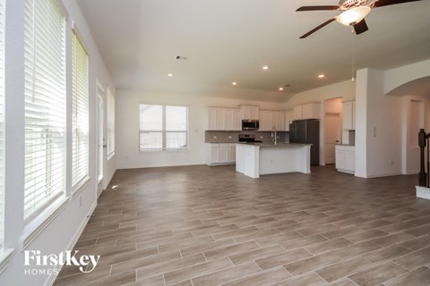 A spacious kitchen and living room with a ceiling fan and lighting.