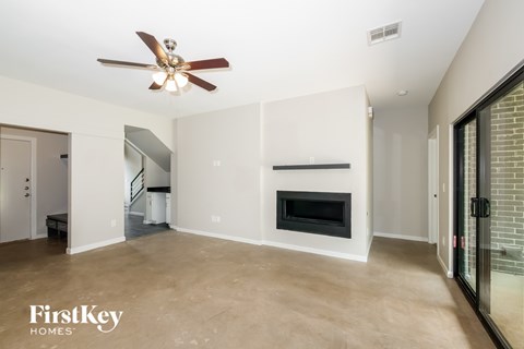 A spacious living room with a fireplace and a ceiling fan.