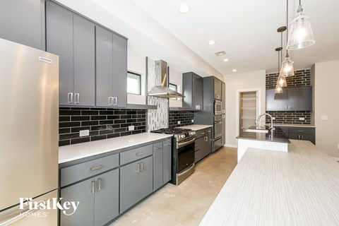 A modern kitchen with a stainless steel refrigerator and dark grey cabinets.